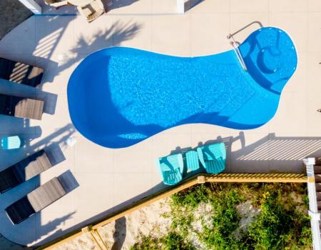 A boardwalk to Holden Beach from a vacation rentals back deck besides a pool