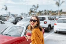 A woman holds keys to her car in a parking lot