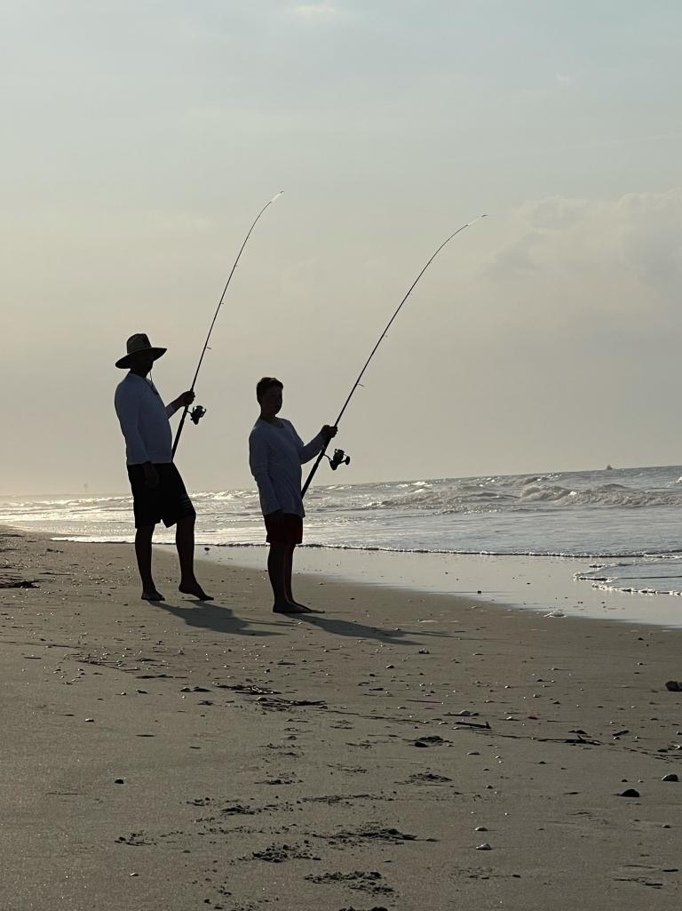 Two people fish at dawn on holden beach