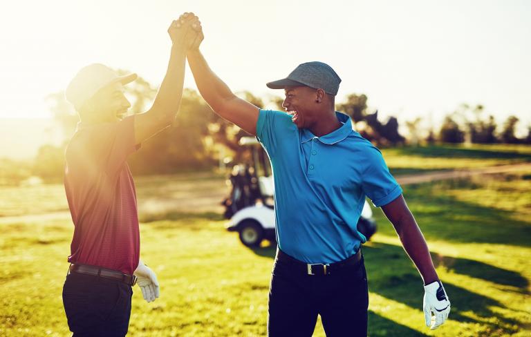 Two golfers give each other a high five after their game of golf