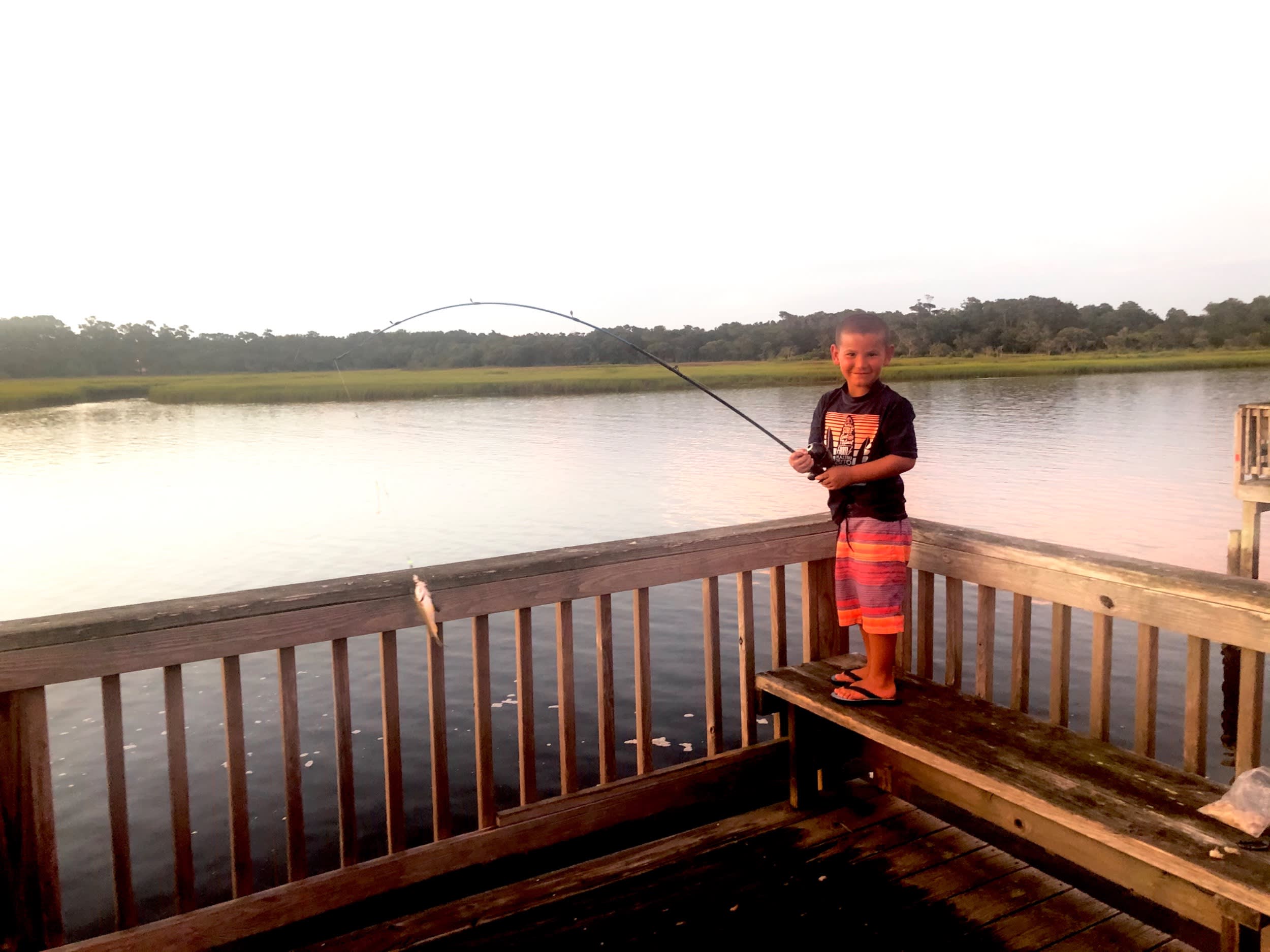 A boy reels in a fish from Holden Beach Peir