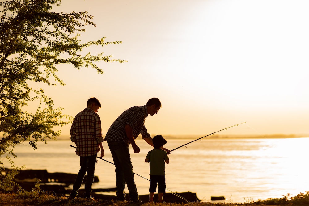 father and sons fish at dusk